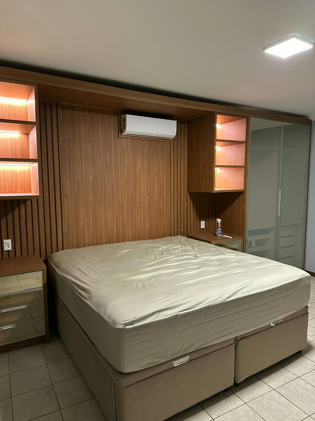Quarto de casal planejado com painel em madeira e nichos iluminados